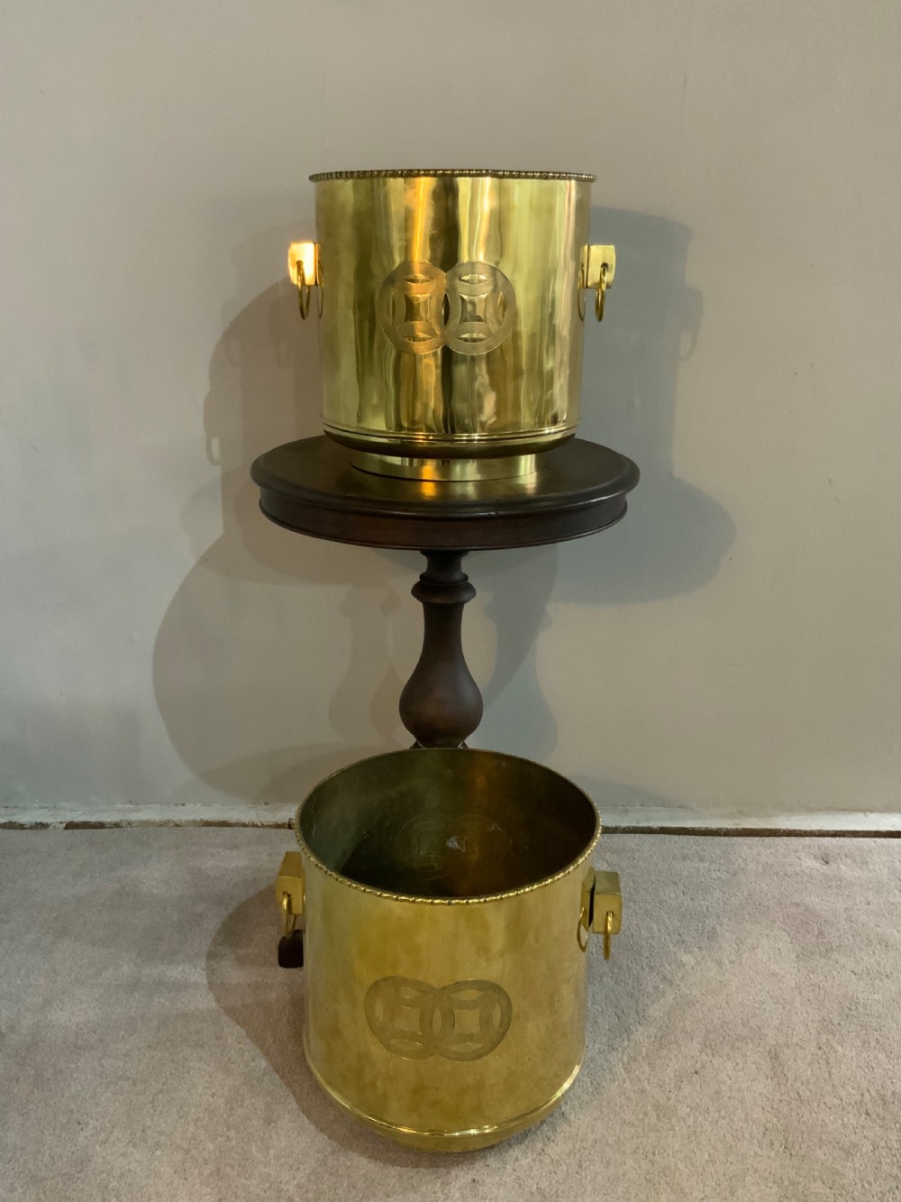 A pair of cylindrical polished brass planters featuring beaded rims, drop ring handles, and etched interlocking circle motifs.