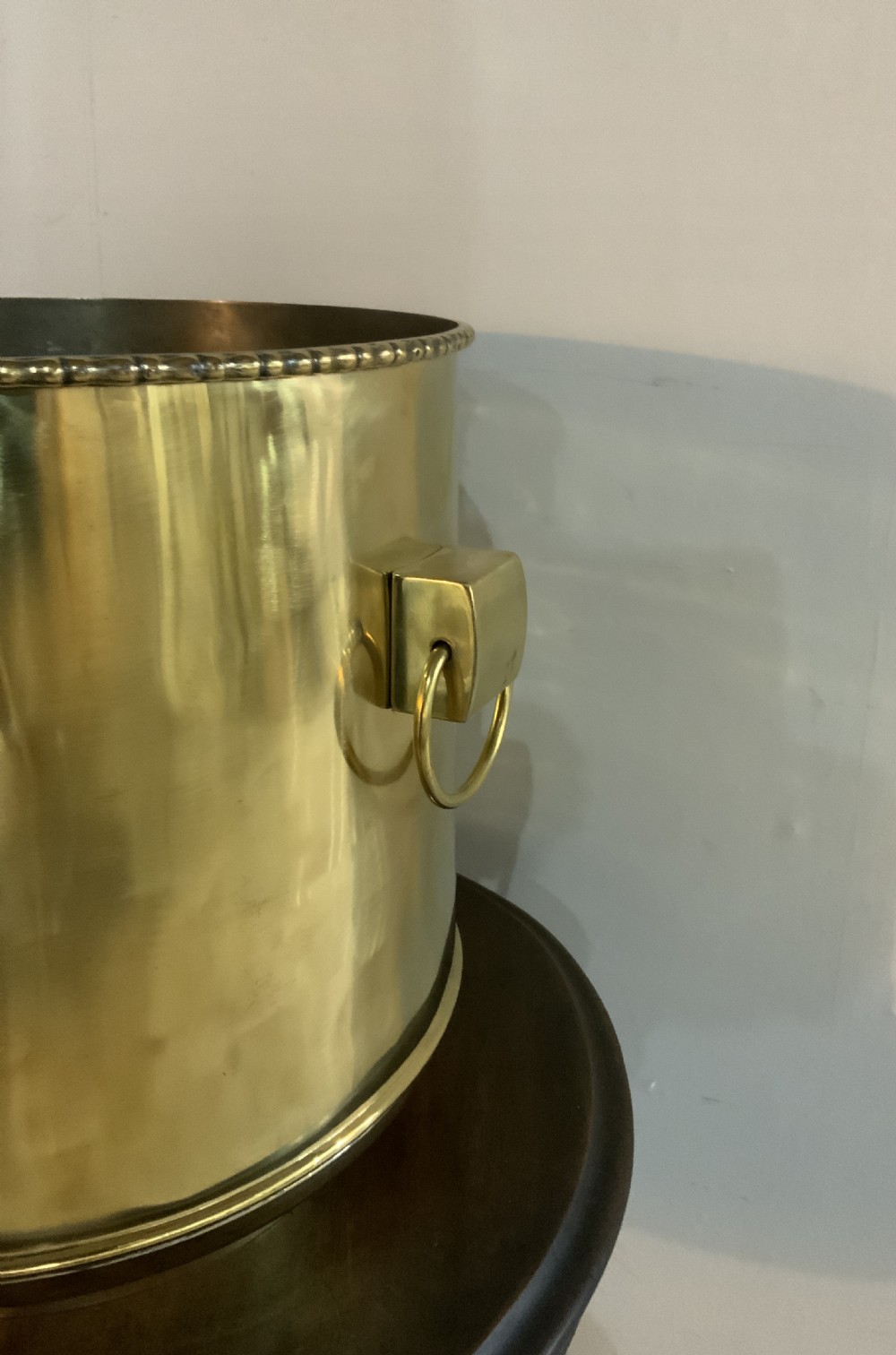 A pair of cylindrical polished brass planters featuring beaded rims, drop ring handles, and etched interlocking circle motifs. View II