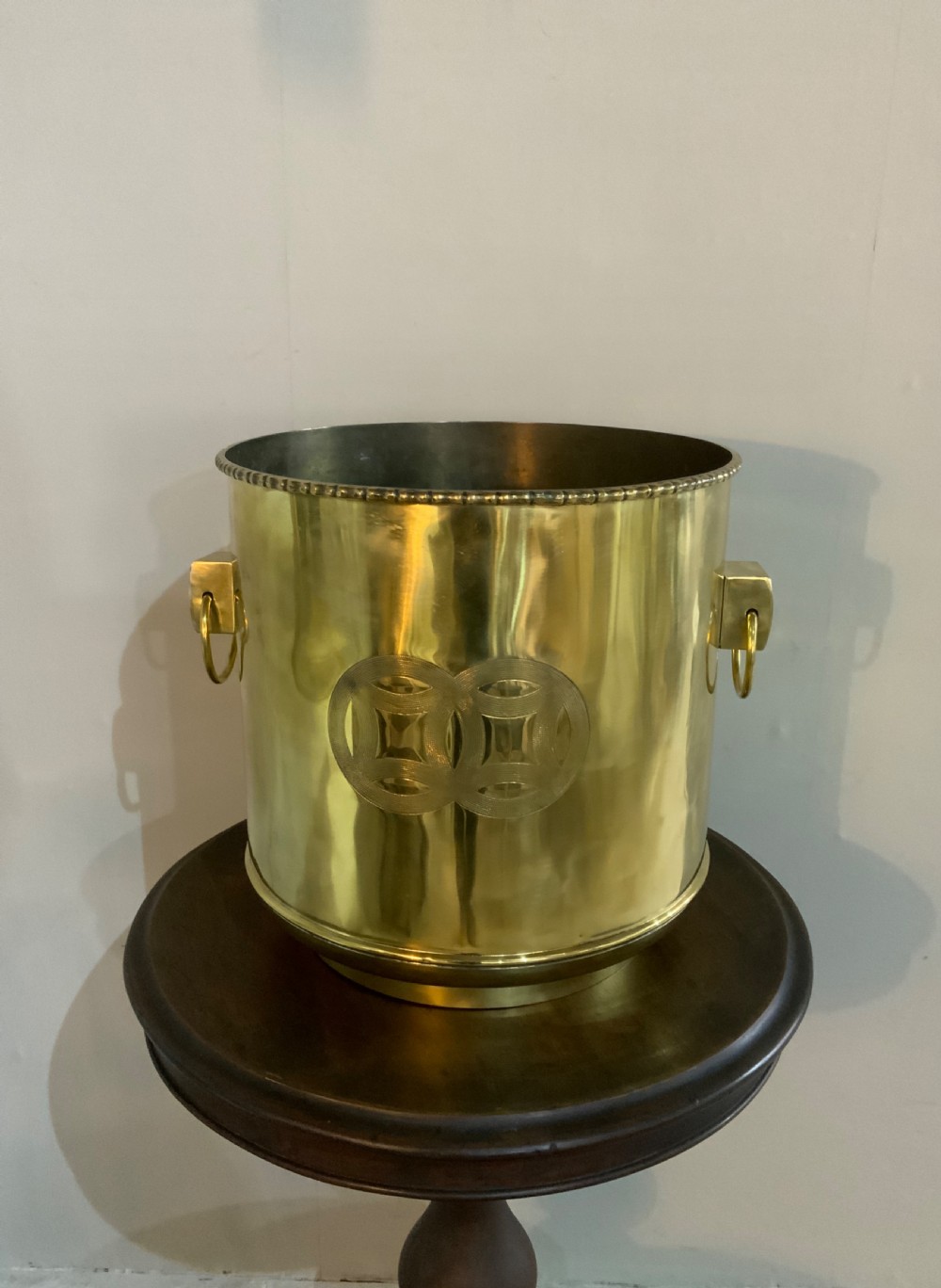 A pair of cylindrical polished brass planters featuring beaded rims, drop ring handles, and etched interlocking circle motifs. View III