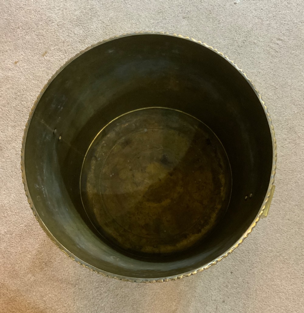 A pair of cylindrical polished brass planters featuring beaded rims, drop ring handles, and etched interlocking circle motifs. View VII