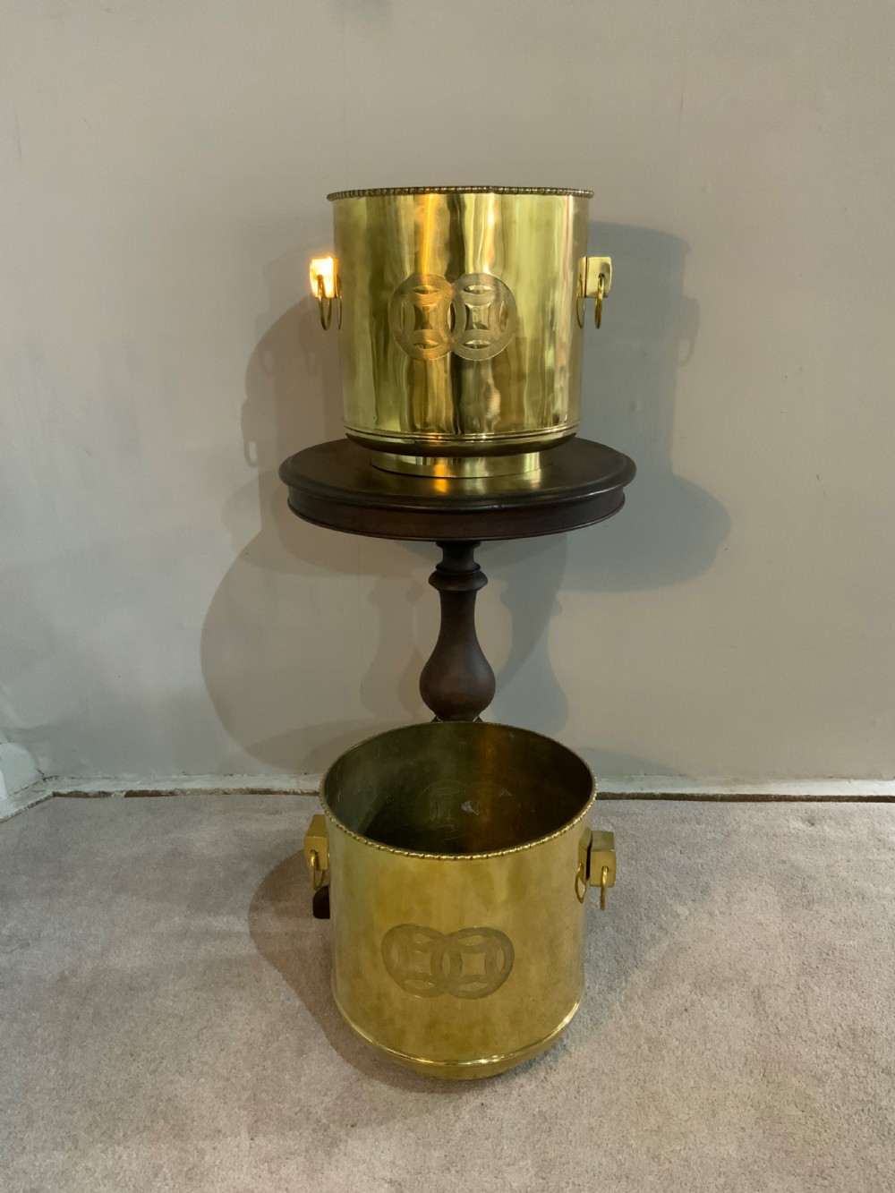 A pair of cylindrical polished brass planters featuring beaded rims, drop ring handles, and etched interlocking circle motifs. View VIII