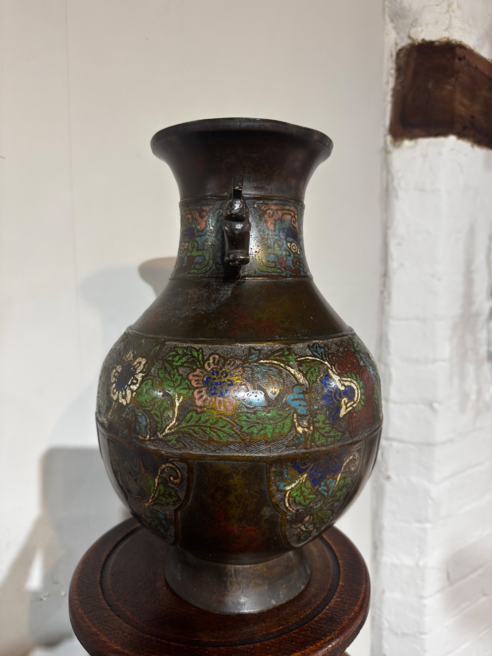 A dark patinated bronze vase with twin dragon handles and polychrome floral champleve enamelling around the body and neck. View III