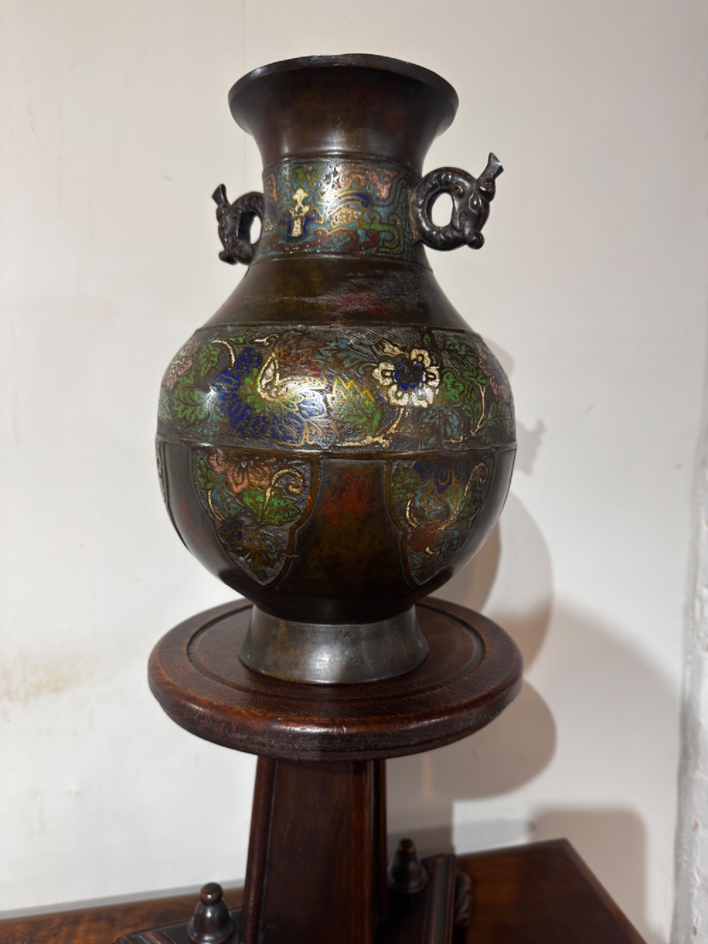 A dark patinated bronze vase with twin dragon handles and polychrome floral champleve enamelling around the body and neck. View IV
