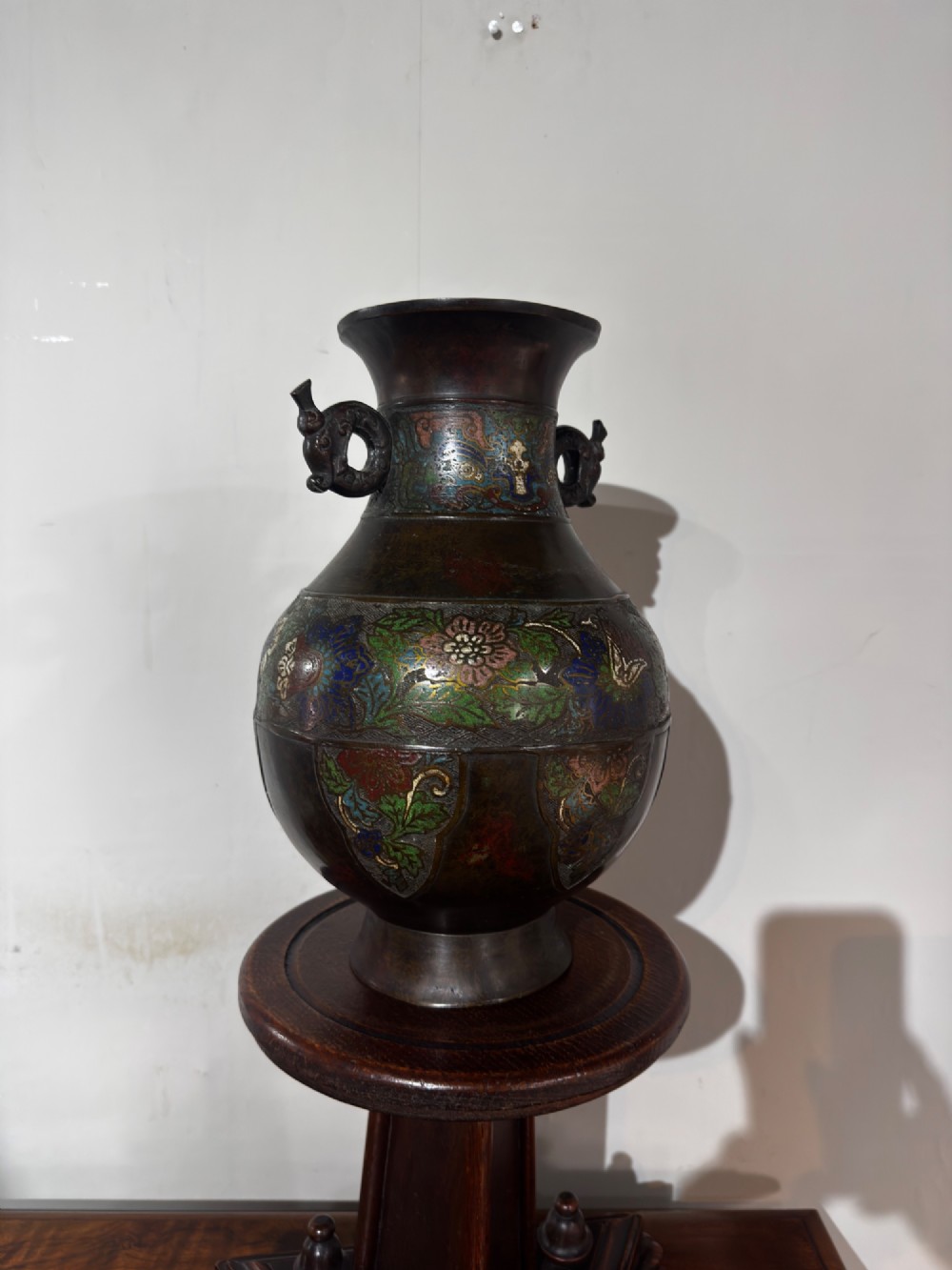 A dark patinated bronze vase with twin dragon handles and polychrome floral champleve enamelling around the body and neck. View V
