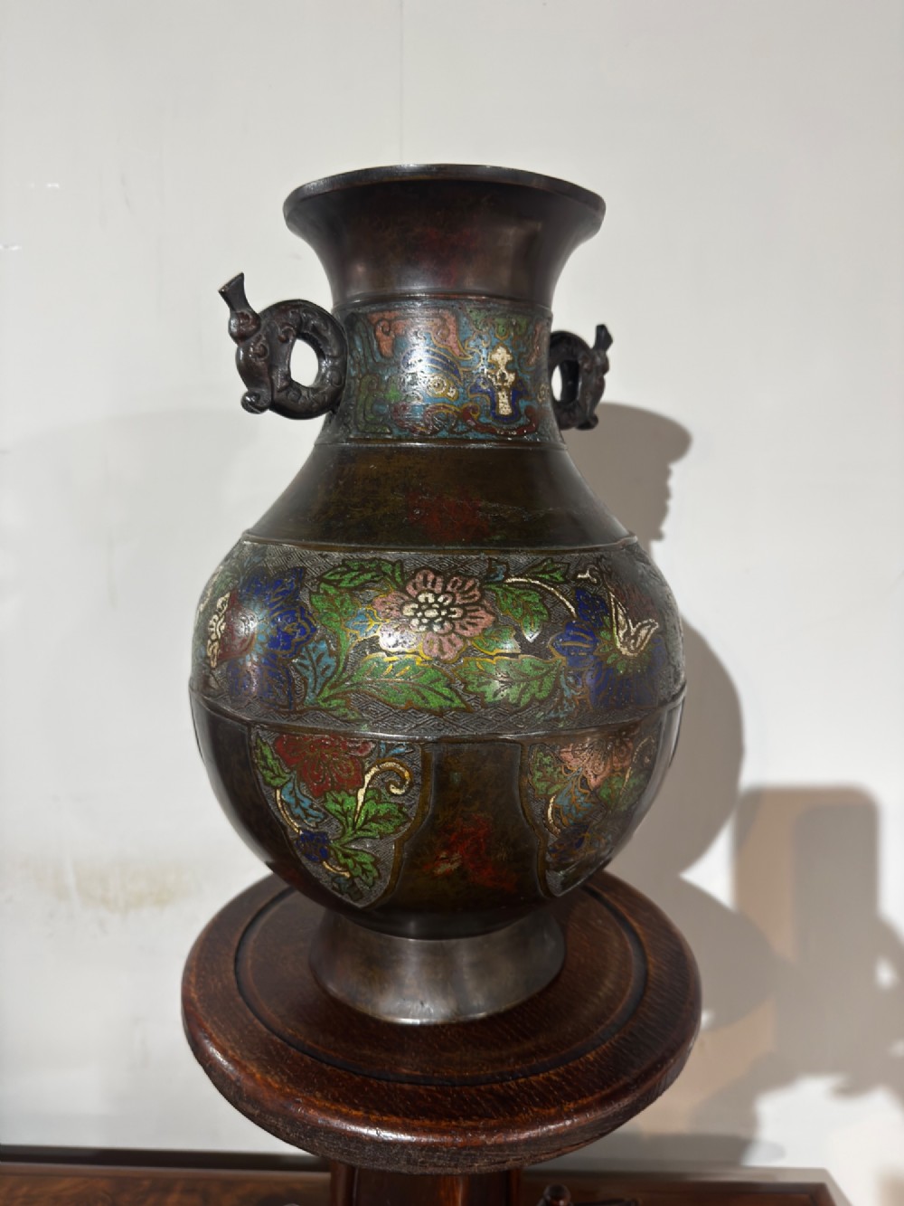 A dark patinated bronze vase with twin dragon handles and polychrome floral champleve enamelling around the body and neck. View VI