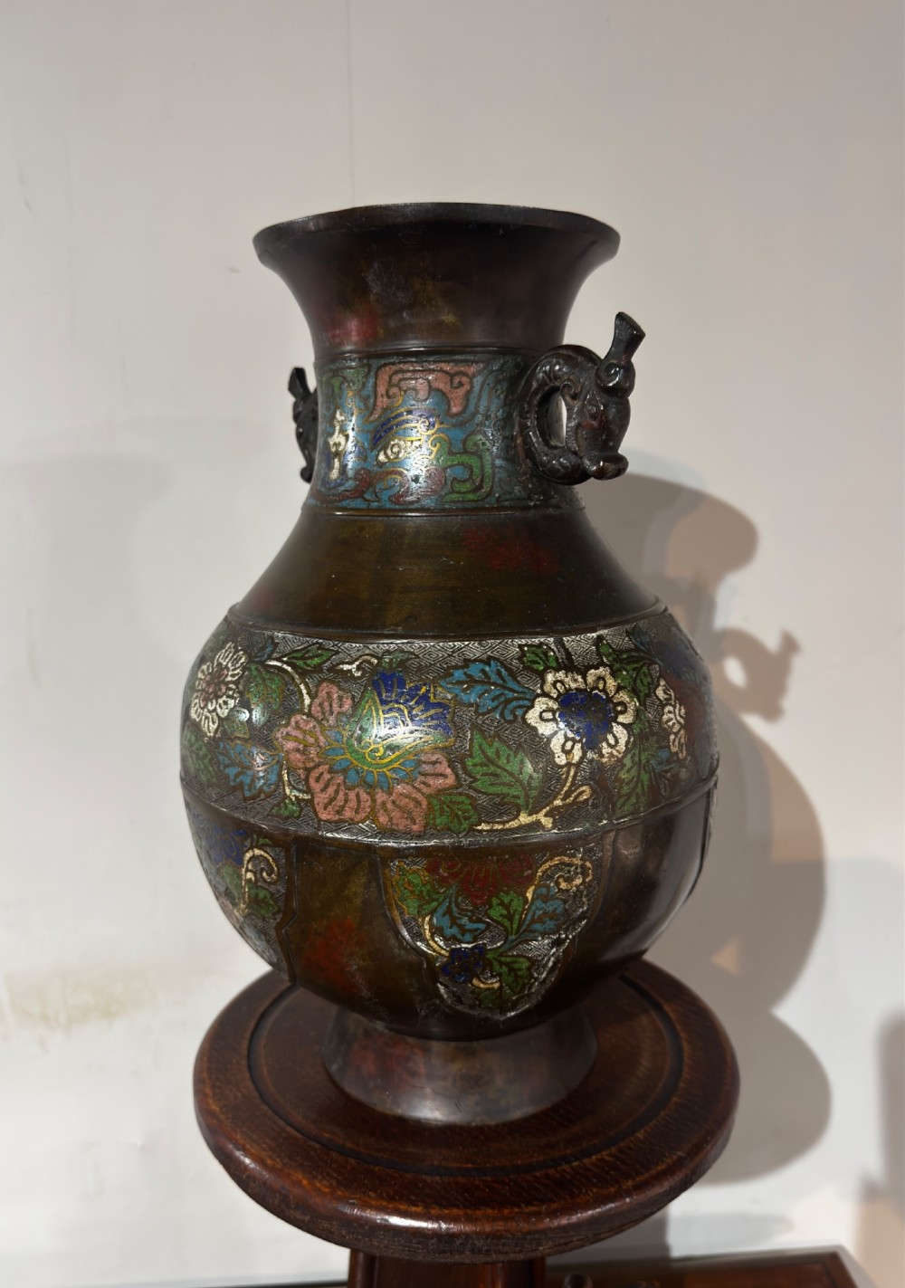 A dark patinated bronze vase with twin dragon handles and polychrome floral champleve enamelling around the body and neck. View VII