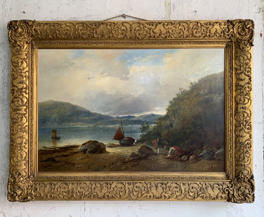 A 19th-century oil painting on canvas showing a coastal shoreline with sailing vessels, framed in an ornate gilded gesso frame.