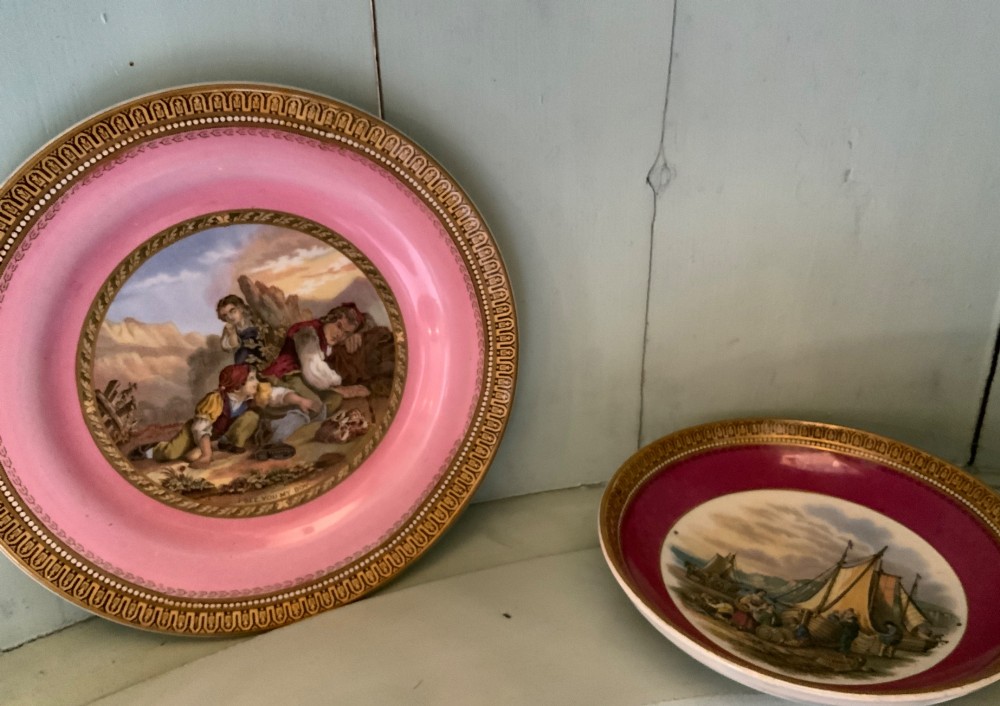 A twelve-piece collection of Victorian English Staffordshire Prattware ceramics including plates, mugs, and dishes with transfer-printed pictorial scenes and pink and gold borders. View V