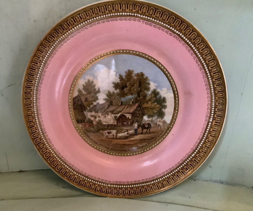 A twelve-piece collection of Victorian English Staffordshire Prattware ceramics including plates, mugs, and dishes with transfer-printed pictorial scenes and pink and gold borders. View VI