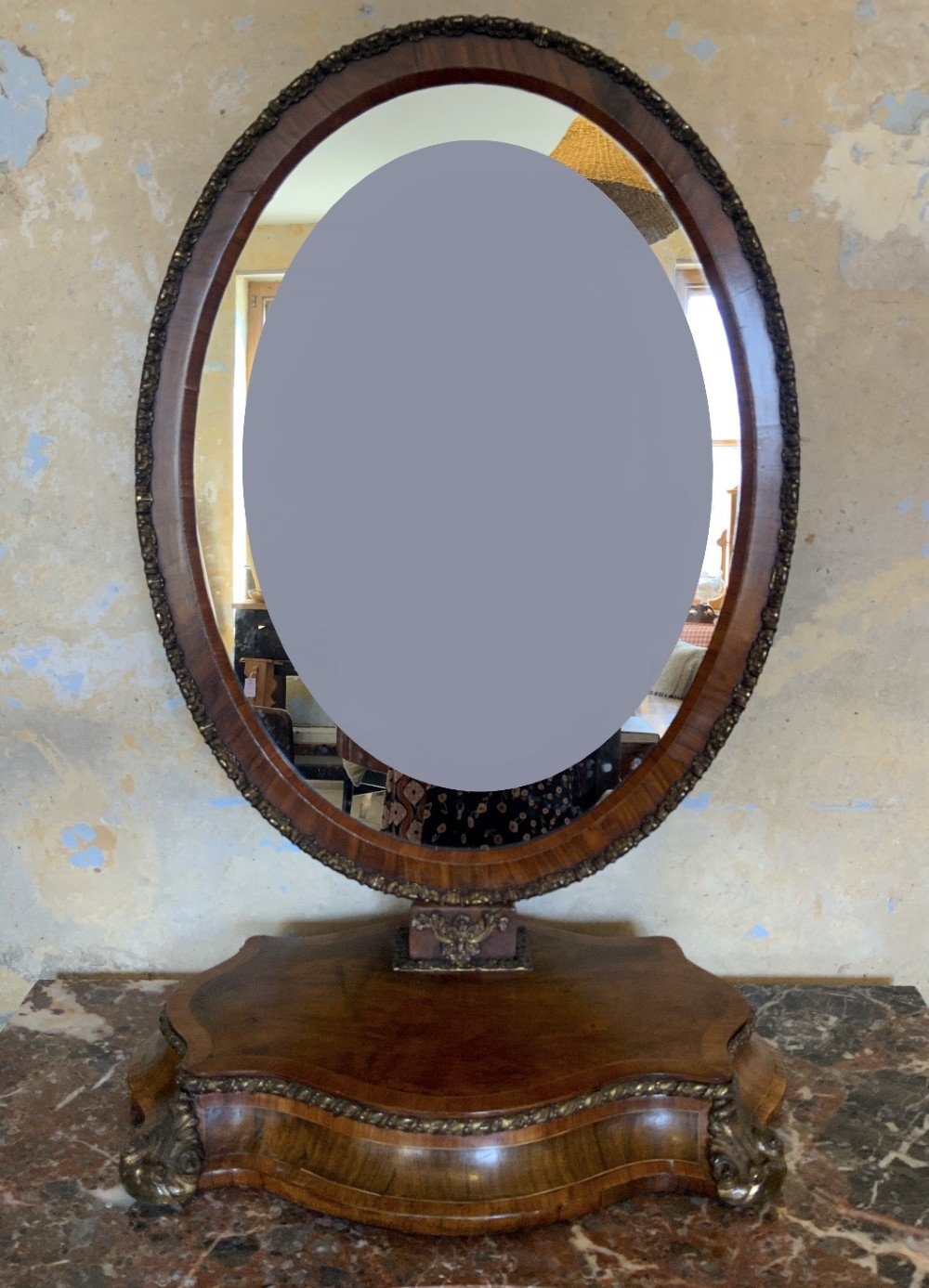 An oval walnut toilet mirror with an ormolu beaded border resting on a shaped serpentine base.