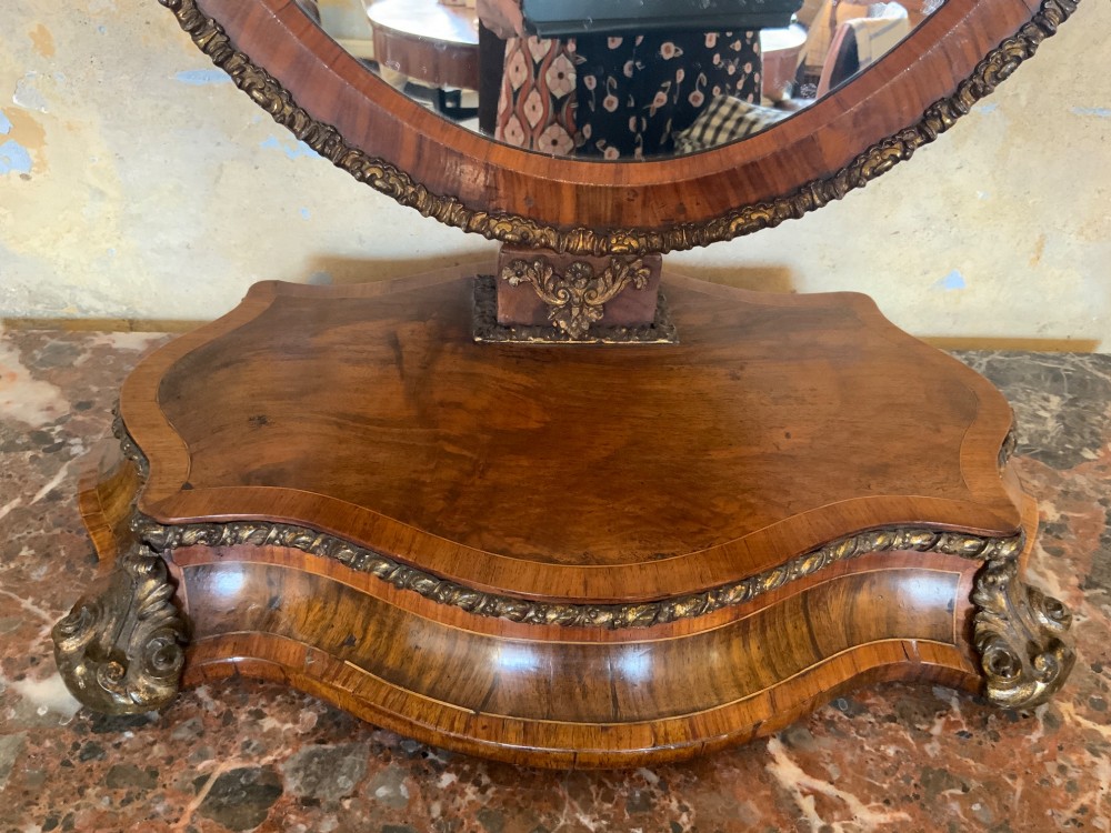 An oval walnut toilet mirror with an ormolu beaded border resting on a shaped serpentine base. View II