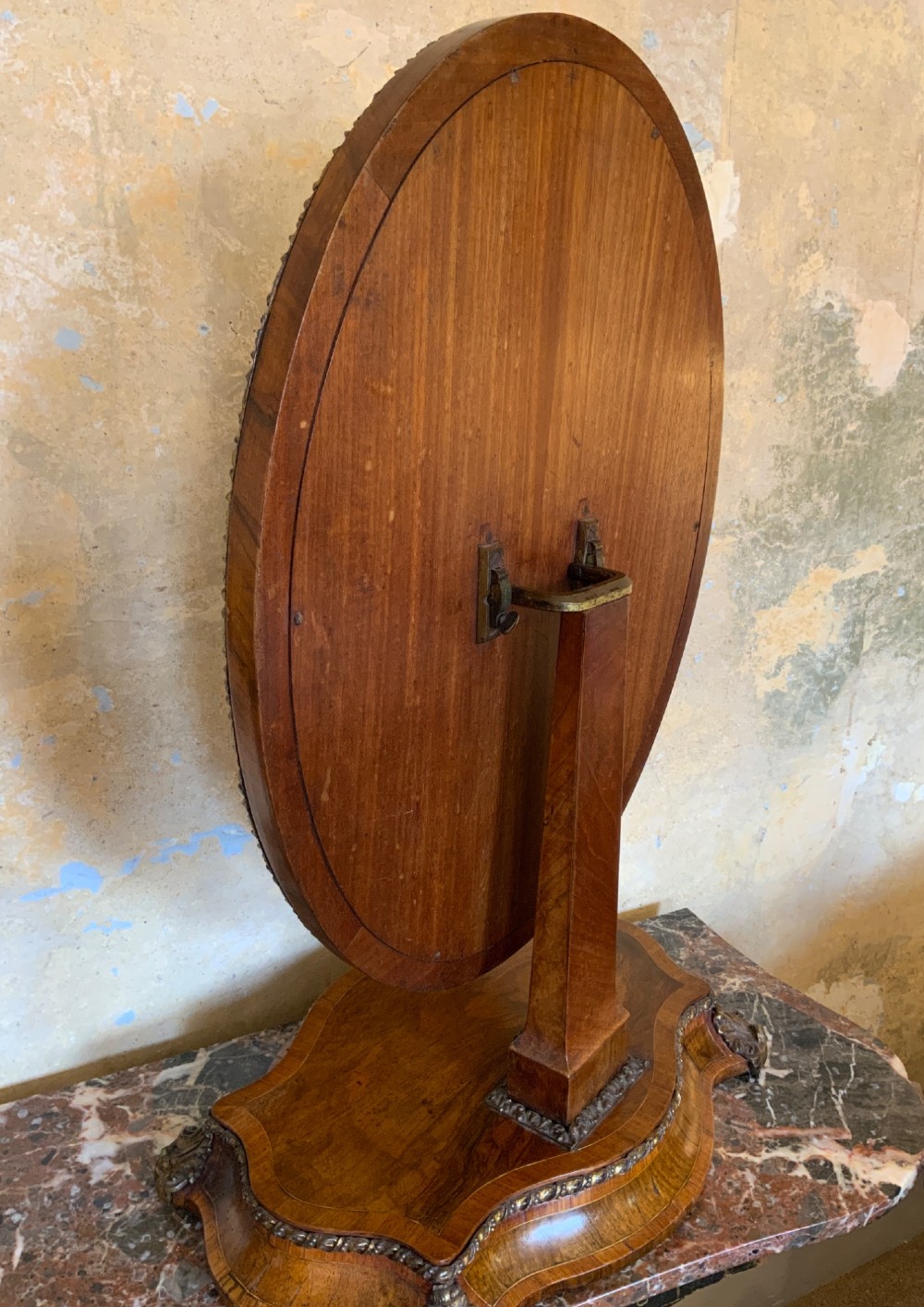 An oval walnut toilet mirror with an ormolu beaded border resting on a shaped serpentine base. View IV