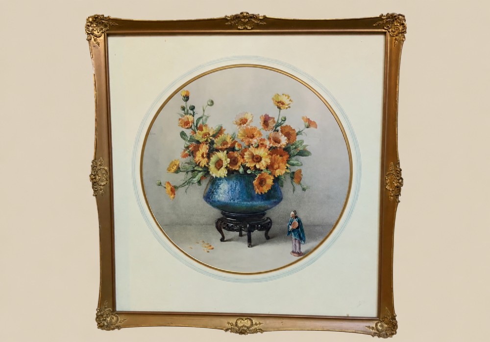 A square gilded framed watercolour painting displaying yellow and orange marigolds in a blue vessel alongside a small Chinese figurine.