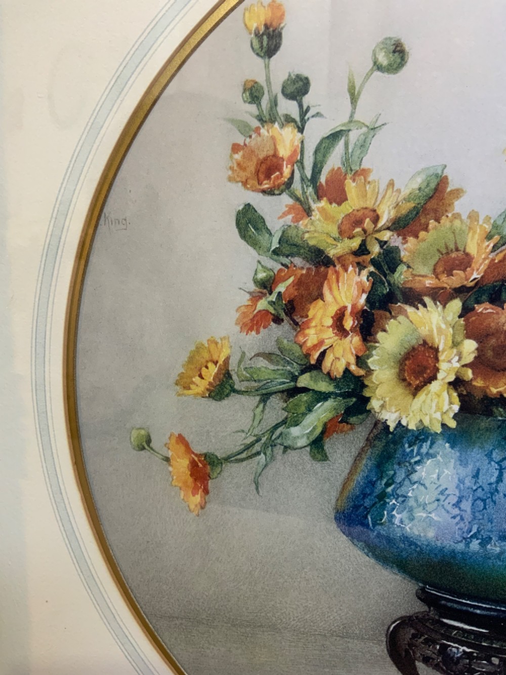 A square gilded framed watercolour painting displaying yellow and orange marigolds in a blue vessel alongside a small Chinese figurine. View IV