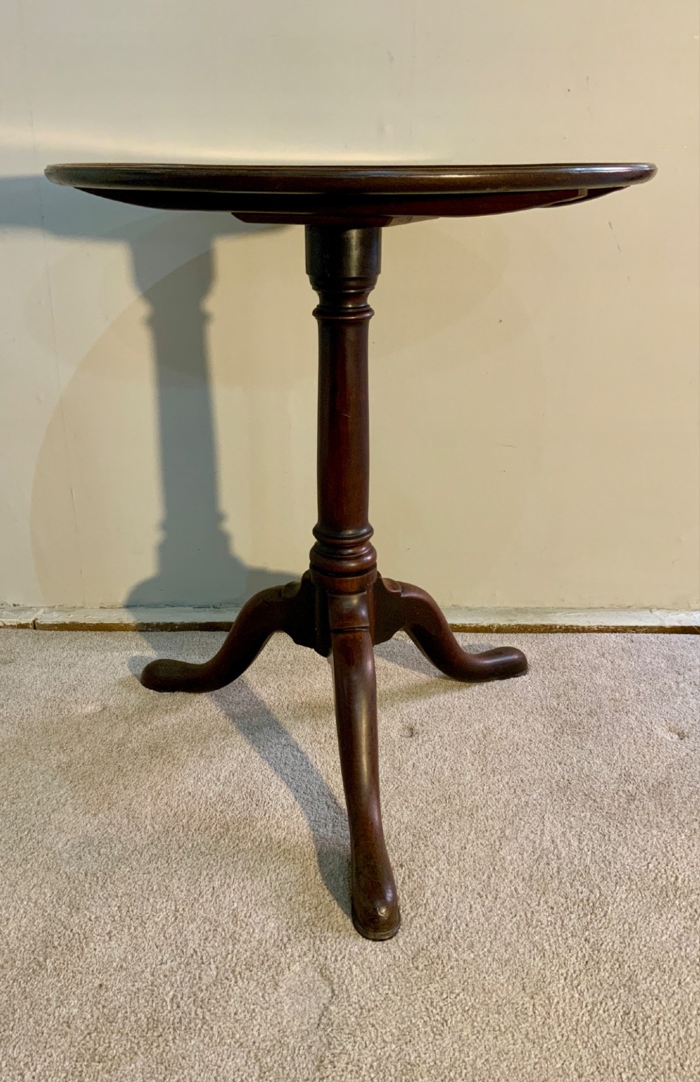 A Georgian solid mahogany tripod table featuring a circular tray top with a raised rim, tilted vertically on a turned central pedestal with three cabriole legs. View II
