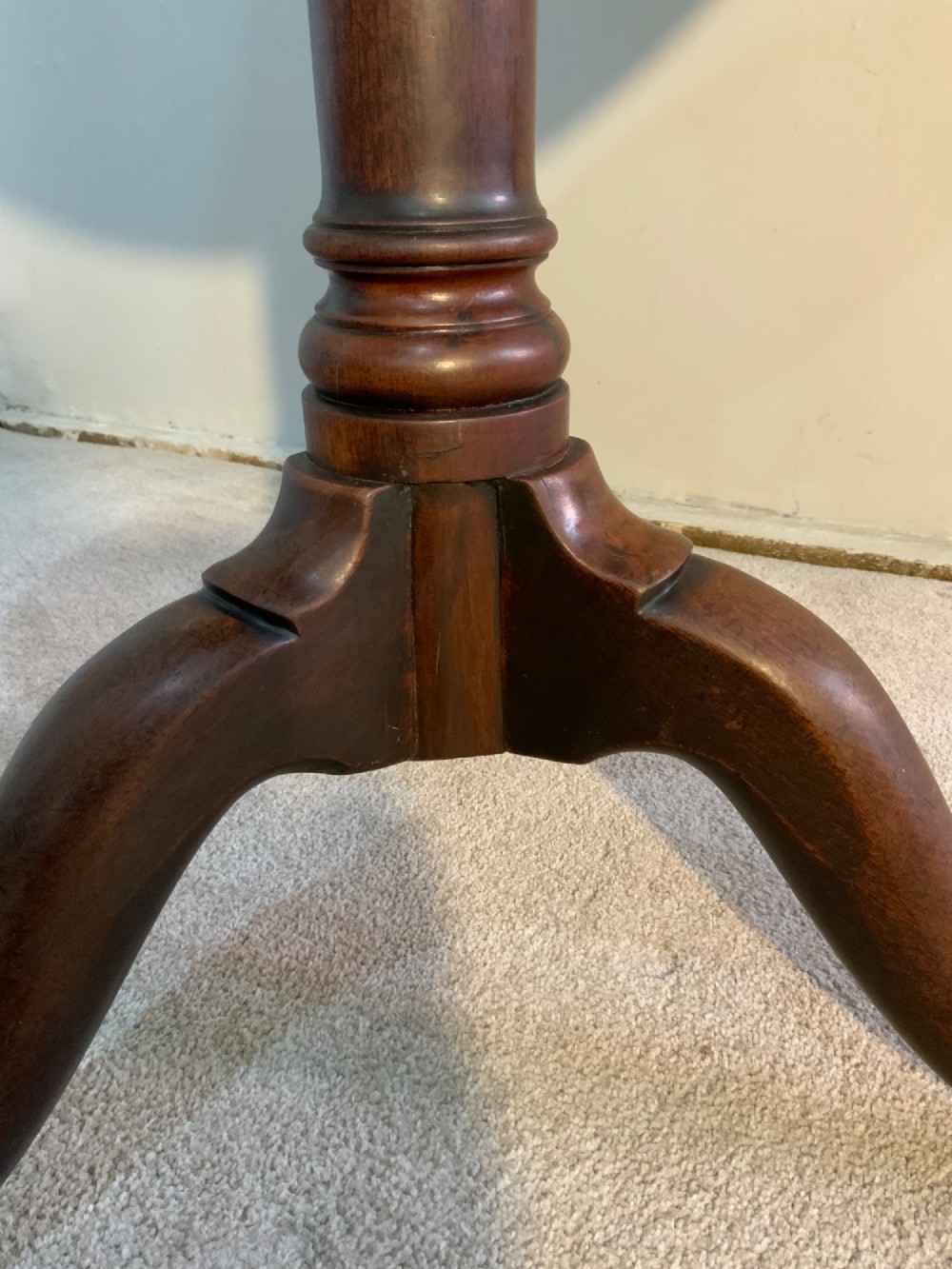 A Georgian solid mahogany tripod table featuring a circular tray top with a raised rim, tilted vertically on a turned central pedestal with three cabriole legs. View VI