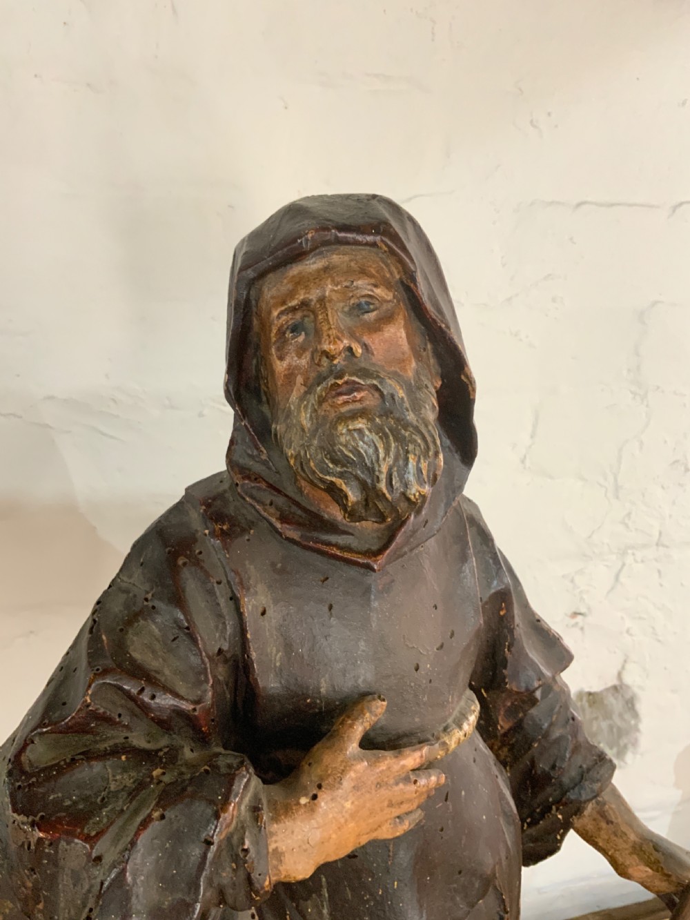 A late 17th century carved wooden figure of a bearded saint wearing a hooded robe and holding a walking staff. View II