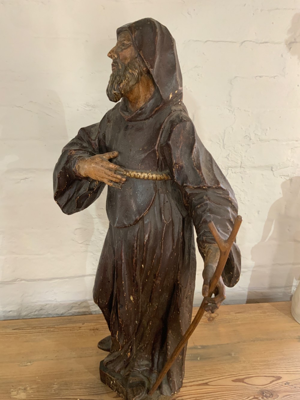 A late 17th century carved wooden figure of a bearded saint wearing a hooded robe and holding a walking staff. View V