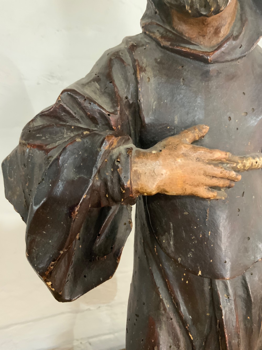 A late 17th century carved wooden figure of a bearded saint wearing a hooded robe and holding a walking staff. View VII
