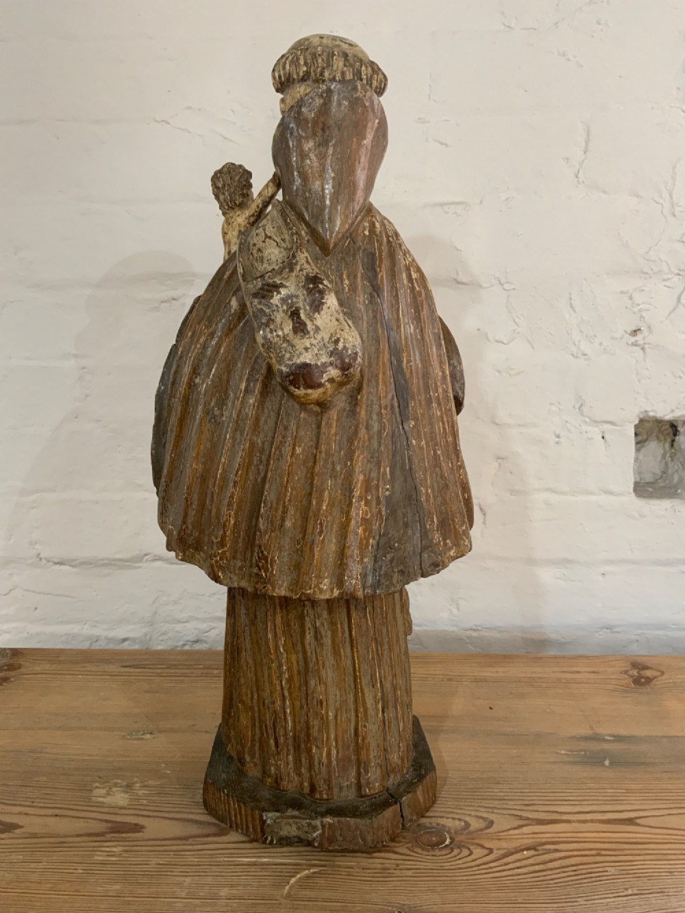 A carved wood figure representing Saint Anthony of Padua in a Franciscan habit holding the Christ Child on a open book. View III