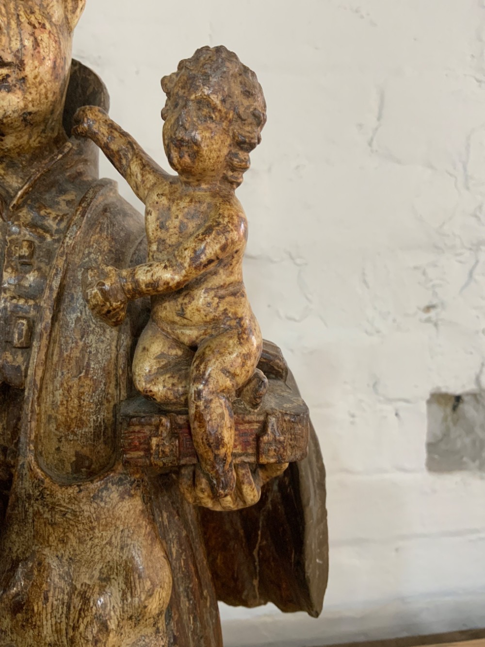 A carved wood figure representing Saint Anthony of Padua in a Franciscan habit holding the Christ Child on a open book. View V