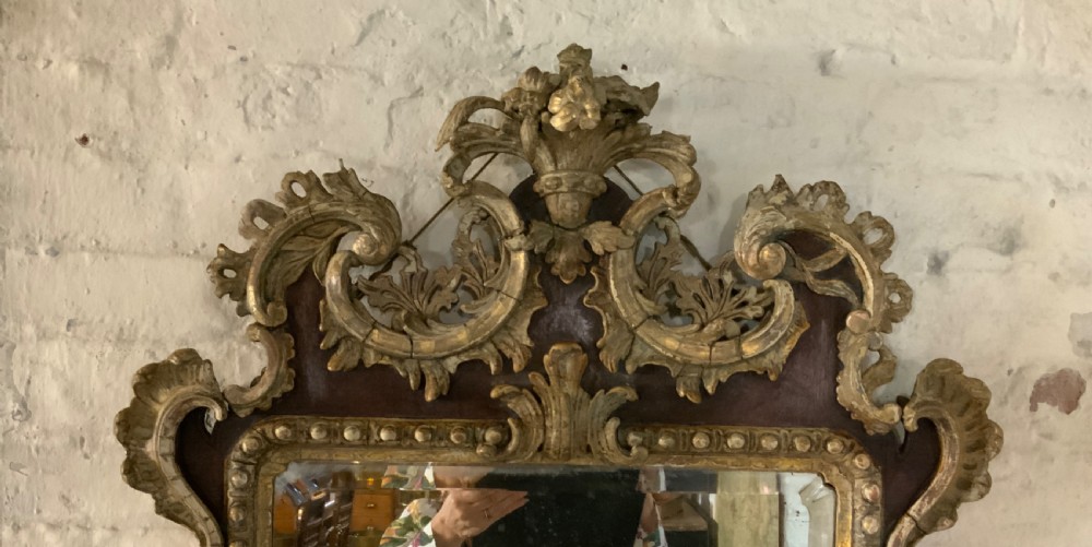 An 18th-century rectangular walnut wall mirror featuring elaborate parcel gilt carved cresting, bead moulding, and a decorative scrollwork apron. View II