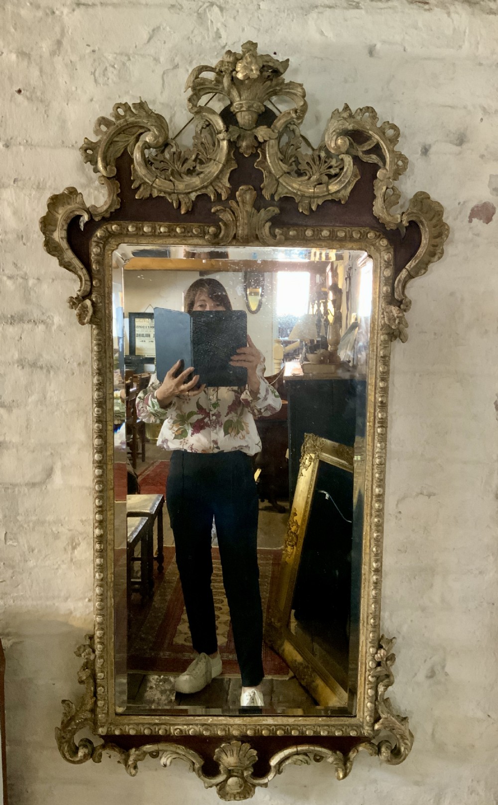 An 18th-century rectangular walnut wall mirror featuring elaborate parcel gilt carved cresting, bead moulding, and a decorative scrollwork apron.
