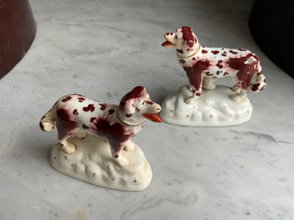 A facing pair of antique ceramic dog figurines decorated with rust-red painted patches on white bases with gilded collars. View VI