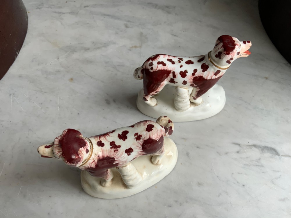 A facing pair of antique ceramic dog figurines decorated with rust-red painted patches on white bases with gilded collars. View VIII