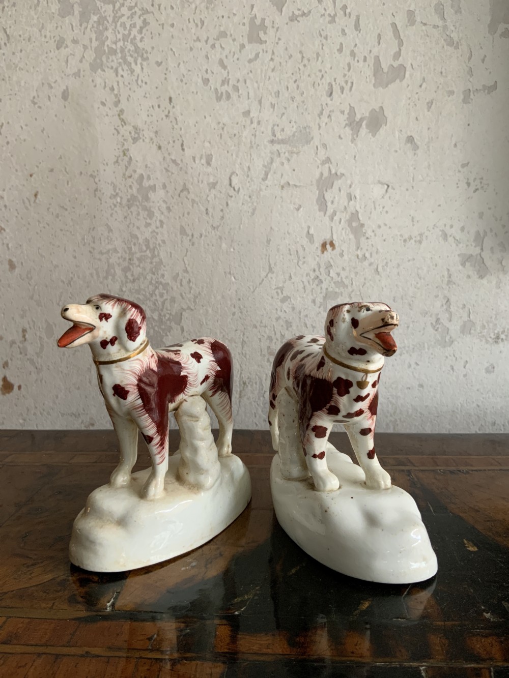 A facing pair of antique ceramic dog figurines decorated with rust-red painted patches on white bases with gilded collars. View IX