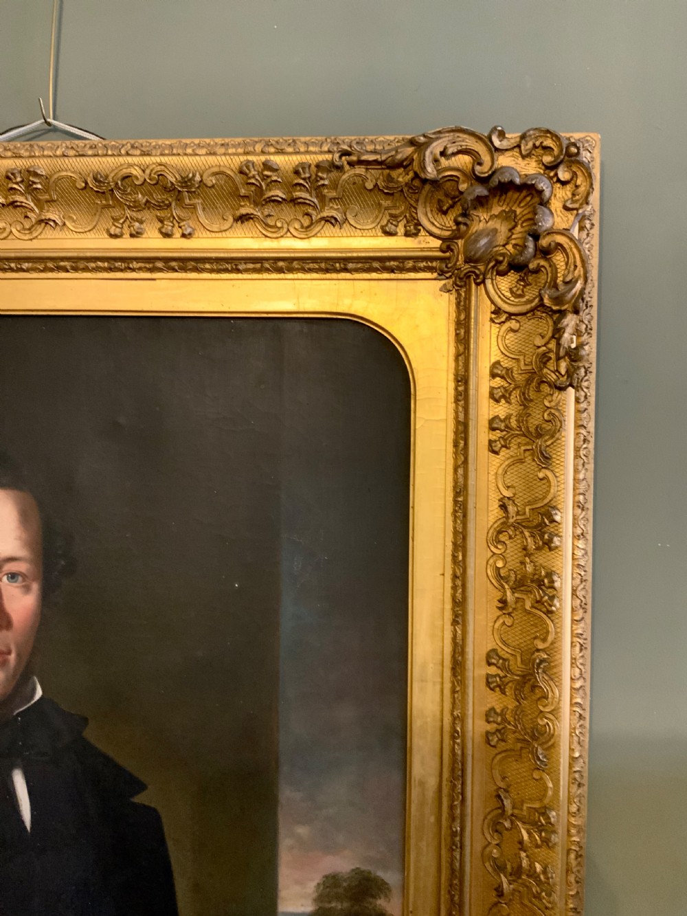A 19th-century oil portrait of a gentleman in a dark suit seated within an ornate gilded frame. View V