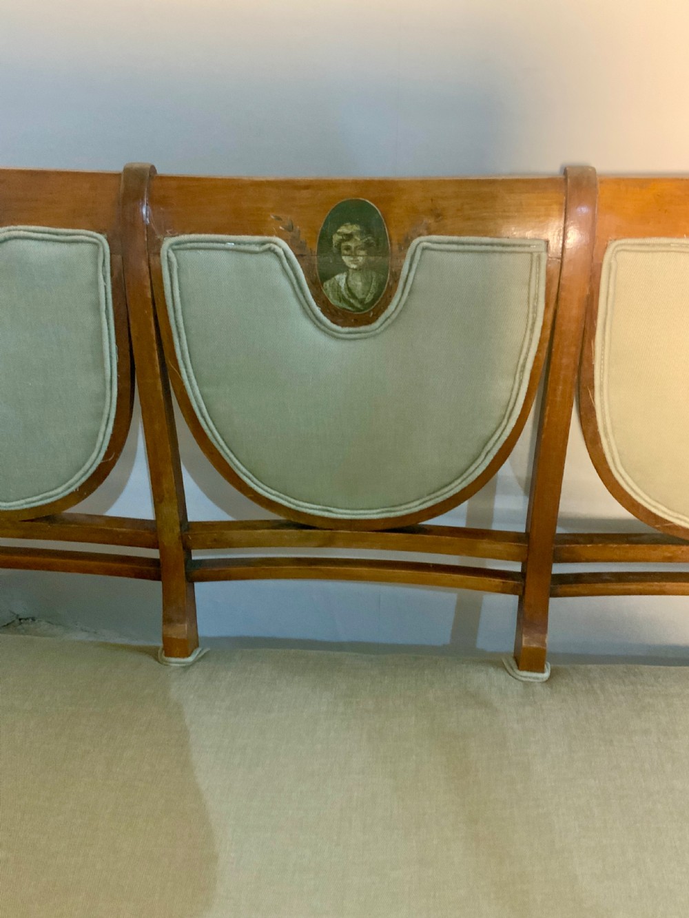 An early 19th-century Regency satinwood chair-back settee featuring three painted portrait medallions and light green fabric upholstery. View III