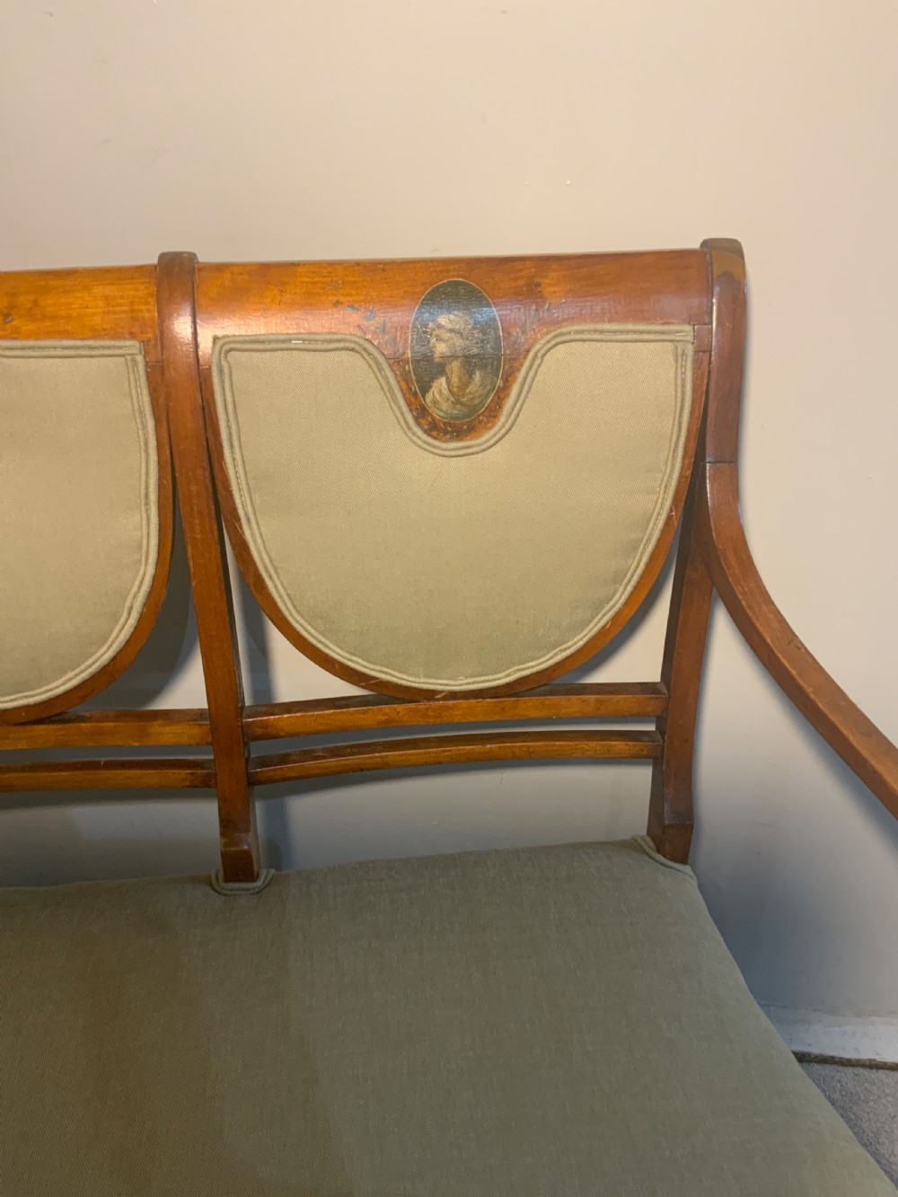 An early 19th-century Regency satinwood chair-back settee featuring three painted portrait medallions and light green fabric upholstery. View IV