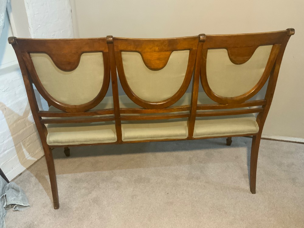 An early 19th-century Regency satinwood chair-back settee featuring three painted portrait medallions and light green fabric upholstery. View VI