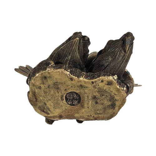 fig 3. A pair of cast bronze doves with detailed feather chasing and fanned tail feathers perched together on a maize cob base.