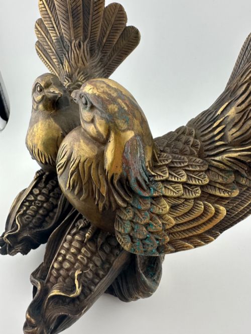 fig 4. A pair of cast bronze doves with detailed feather chasing and fanned tail feathers perched together on a maize cob base.