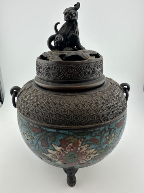 fig 1. A 19th-century Chinese bronze tripod censer featuring polychrome cloisonne enamel floral motifs, side loop handles, and a lid topped with a Qilin finial.