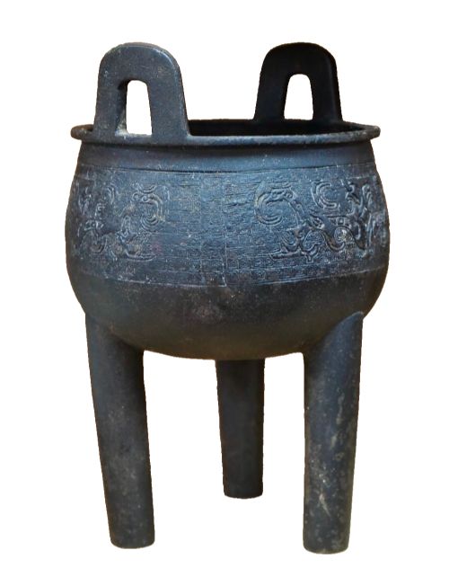 fig 2. A dark patinated bronze tripod ding censer featuring three cylindrical legs, twin upright handles, and carved taotie mask relief decoration around the upper body.