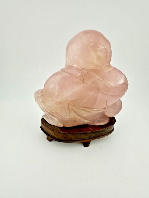 fig 1. A hand-carved pink rose quartz figure of a seated Laughing Buddha resting upon a custom dark wood stand.