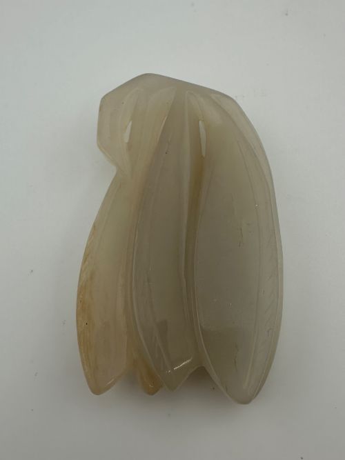 fig 1. A carved pale celadon jade sculpture depicting a cicada with folded wings and smooth polished surfaces.