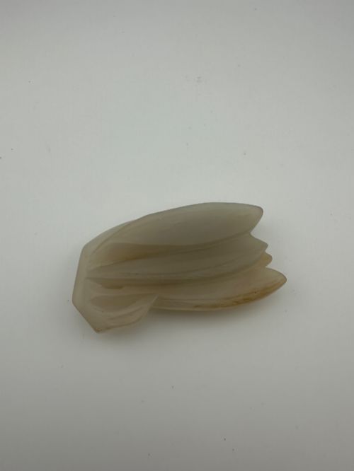 fig 2. A carved pale celadon jade sculpture depicting a cicada with folded wings and smooth polished surfaces.