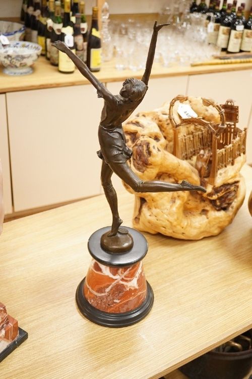 fig 4. An Art Deco style bronze sculpture of a female dancer in mid-leap mounted on a rounded variegated orange marble base.