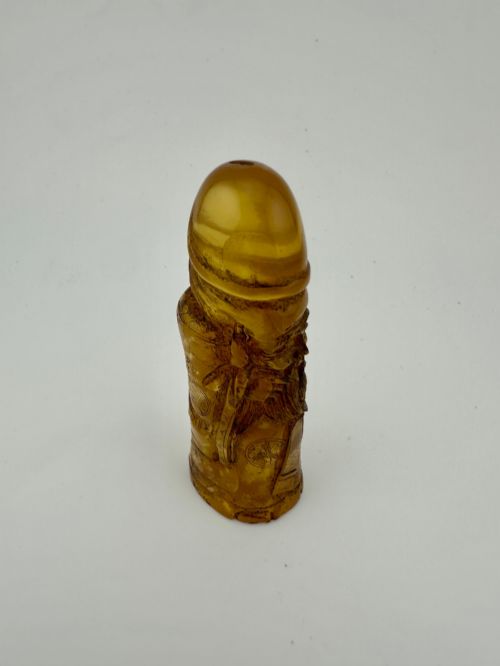 fig 5. A hand-carved honey amber pendant depicting the Chinese deity Shoulao with incised robe detailing and a high domed head.