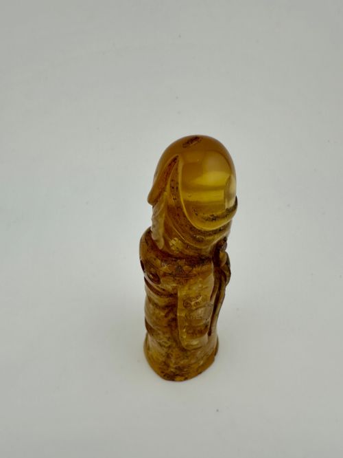 fig 6. A hand-carved honey amber pendant depicting the Chinese deity Shoulao with incised robe detailing and a high domed head.