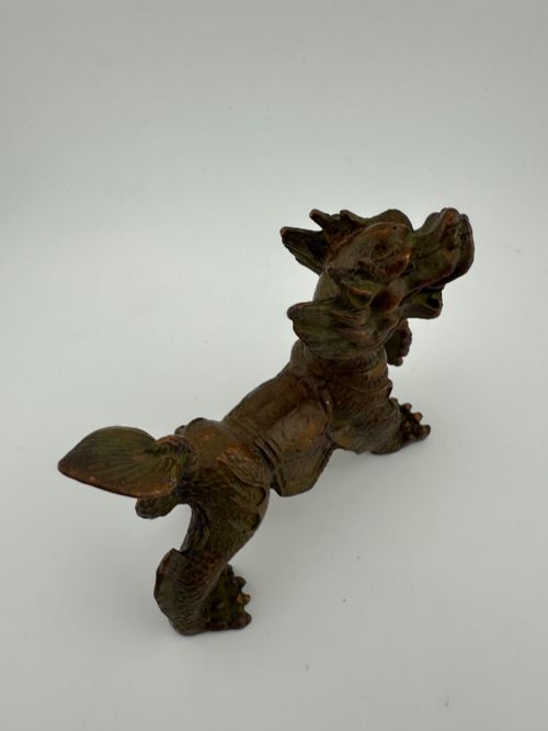 fig 2. A small patinated dark brown bronze figure of a Chinese mythical beast, standing on four legs with an open mouth and raised tail.