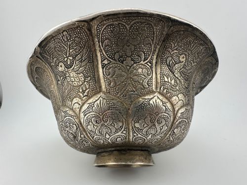fig 1. A lobed silver white metal bowl decorated with hand-chased panels of birds and flowers on a textured ground.