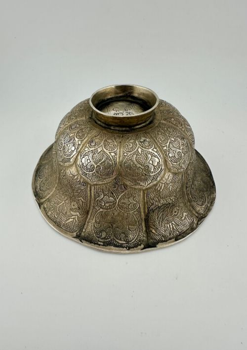 fig 2. A lobed silver white metal bowl decorated with hand-chased panels of birds and flowers on a textured ground.