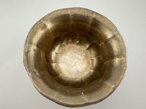 fig 3. A lobed silver white metal bowl decorated with hand-chased panels of birds and flowers on a textured ground.