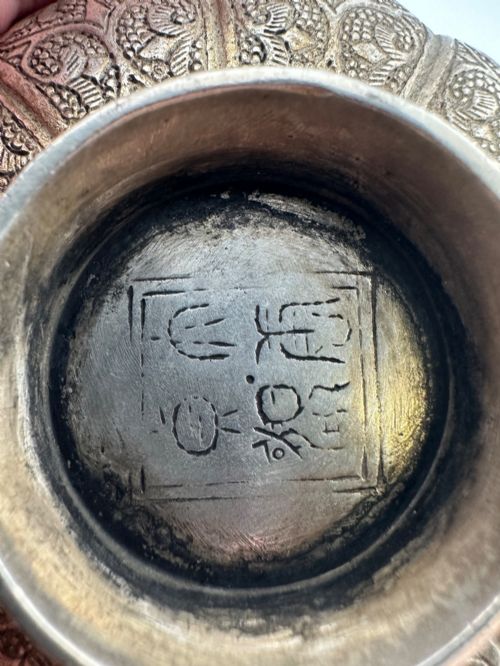 fig 4. A lobed silver white metal bowl decorated with hand-chased panels of birds and flowers on a textured ground.