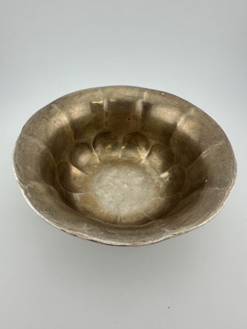 fig 6. A lobed silver white metal bowl decorated with hand-chased panels of birds and flowers on a textured ground.